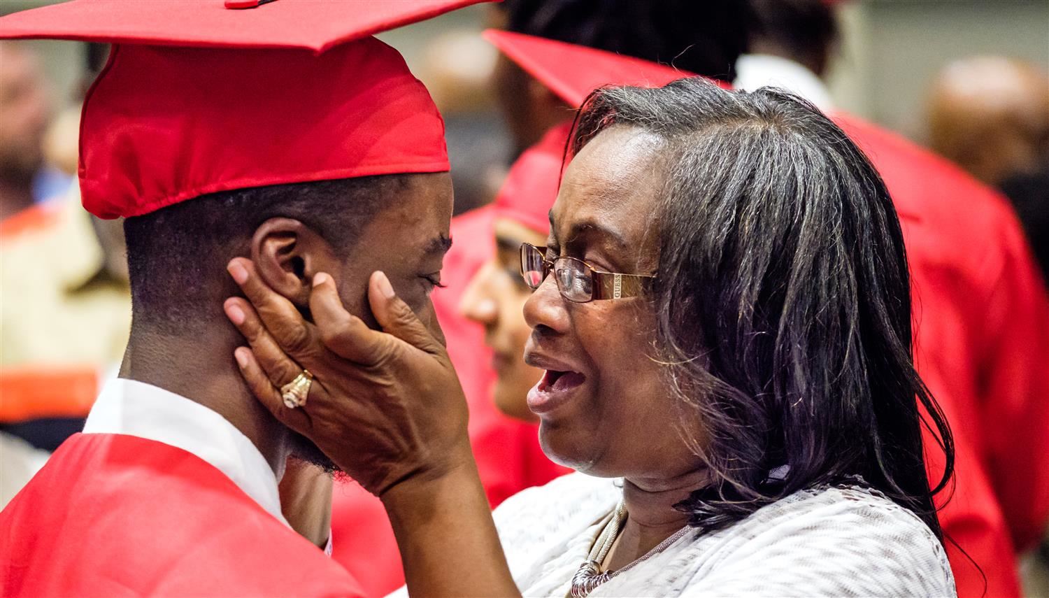 Woman lovingly holding young graduate's face